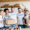 happy-multicultural-women-holding-cardboard-box-and-paper-bag-with-apples-while-standing-near.jpg